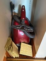 Red Kenmore 400 Series vacuum cleaner with hose and vacuum bags on floor in corner.