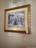 Full view of framed beach scene painting on wall showing people under umbrellas.