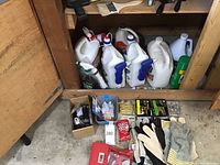 Bottles of cleaning chemicals on bottom shelf with gloves and tools in front