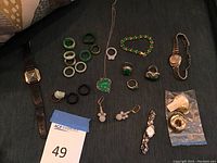 Overview of watches, bangles, rings, earrings and necklace laid out on table