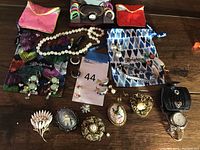 Complete lot showing assortment of costume jewelry on wooden surface with small pouches and gift bags