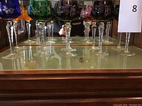 Six colored cut crystal goblets arranged on mirrored surface