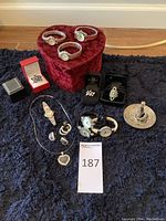 Full view of all included jewelry items, watches, trinket dish, and heart-shaped box on a dark fabric background.