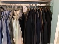 Wide shot of shirts and suit jackets hanging on rod