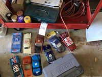 Overview of model car bodies, Dremel tool box, accessory case, paints and soldering iron on red cart