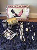 Photo showing the full set with the decorative suitcase and jewelry pieces arranged on a dark blue carpet.