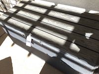 Photo of closed outdoor storage box with dark brown woven rattan style and slatted lid, showing condition and design.