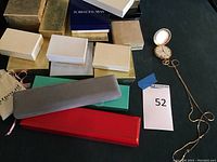 Photo showing all jewelry boxes grouped together with pocket watch and chain laid out to side.