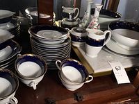 Multiple stacked plates, bowls, cups visible on cabinet shelf