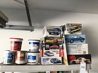Spackling compound, primer, stucco repair products, and boxes of model car kits including Plymouth AAR Cuda and others