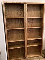 Front view of two matching oak bookcases side by side, showing 5 adjustable shelves each.