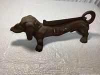 Side view of the cast iron dachshund-shaped mud scraper, showing detailed dog head and front legs.