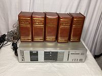 Photo showing Nakamichi BX-1 cassette deck with five brown leather cassette library cases filled with tapes on top.