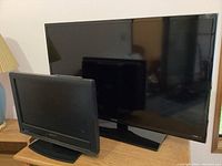 Samsung 39-inch flat screen TV and Emerson 19-inch TV with built-in DVD player on wooden shelf