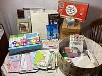 Overall view of the lot showing assorted greeting cards, photo albums in various sizes, and baskets including a large round basket with floral design, and a square woven basket.