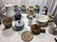 Full view of the pottery set including coffee pot, mugs, bowls, candle holders, salt and pepper shakers, and planter in blue and brown tones.