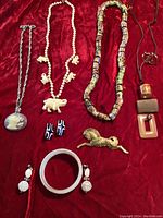 Full lot of vintage costume jewelry laid on red fabric background showing all pieces including necklaces, earrings, bracelet, pins.