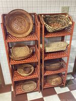 Two rust-colored woven folding shelves with multiple woven wicker baskets of different shapes and sizes arranged on the shelves.
