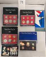 Photo showing four US proof coin sets from 1980 to 1983 and their packaging