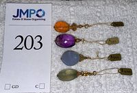 Four pendants displayed on white cloth with JMPO sign and lot number