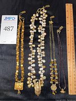 Four necklaces laid on black fabric with ruler showing full set and scale