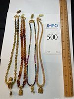 Four necklaces laid alongside ruler showing overall length and scale