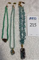 Overall view of three gemstone necklaces on white background with lot ticket
