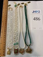 Overhead view of four necklaces laid side by side with ruler for scale