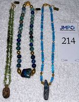 Three necklaces on white cloth: green tourmaline, lapis-style beads, Swiss blue topaz with opal pendants.
