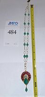 Full necklace laid flat with ruler showing length and emerald bead chain