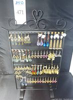Photo of full display rack with multiple rows of dangle earrings in various styles and colors arranged on black metal stand.