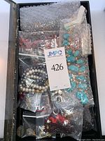 Box with mixed finished jewelry pieces and bead strings