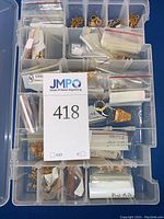 Top view of clear plastic compartment box filled with multiple small bags of gold fill jewelry findings, various sizes and shapes visible.