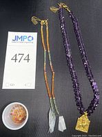 Full lot showing purple beaded necklace, multi-color bead strands, loose beads in cup