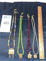 Four necklaces on black background with ruler for scale