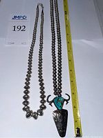 Two necklaces displayed on white background with measuring tape showing lengths