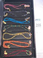 Tray view of seven necklaces showing bead colors and opal pendants