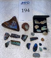 Overview of all opal pieces laid out on white towel, including large triangular slab, rough nodules, raw fragments, polished slabs, and cabochons.