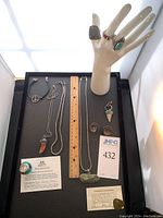 Full tray with bracelets, necklaces, pendants, earrings and pendants displayed alongside certificates and ruler