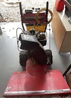 Front view of snow blower and jerry can on bench
