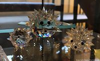 Front view of three Swarovski crystal hedgehog figures on a glass surface showing their faceted spiked backs and black eyes