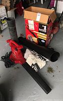 Toro Ultra Blower Vac with three black blower tubes, white cloth bag, and original box on concrete floor.