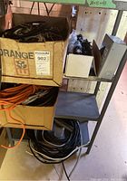Box containing coils of electrical wires and extension cords on metal shelving