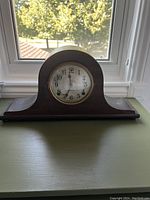 Front view of the Sessions mantle clock with wooden casing and circular clock face showing time.