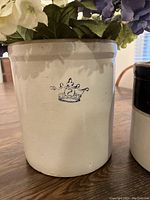 Front view of off-white stoneware crock with blue crown and number 2 decoration.