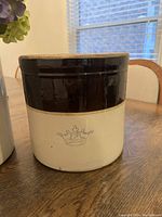 Photo of antique two-tone stoneware crock with crown and '2' mark showing the front, highlighting the color and glaze condition.