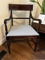 Front view of the wooden captain chair showing the dark wood frame and recently upholstered light grey seat