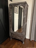 Front view of closed cabinet showing full-length arched mirror and bottom drawer