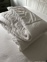 White folded queen size comforter shown on bed.