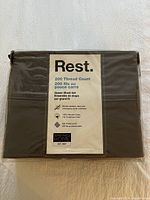 Front view of unopened dark gray sheet set package labeled Rest by Springs Home 200 Thread Count, 100% Cotton.